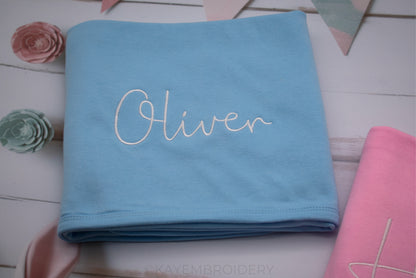 Close up of Blue Cotton Baby Blanket with Name in White Embroidery