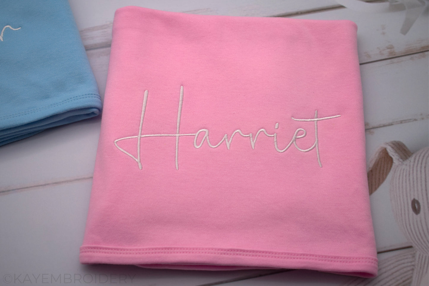 Close up of Blue Cotton Baby Blanket with Name in White Embroidery