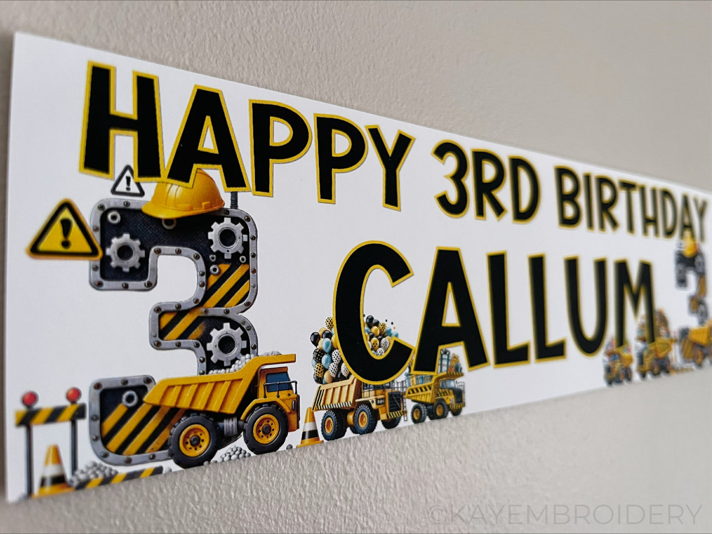 Personalised Birthday Banner featuring a yellow and black construction theme with trucks, gears and balloons