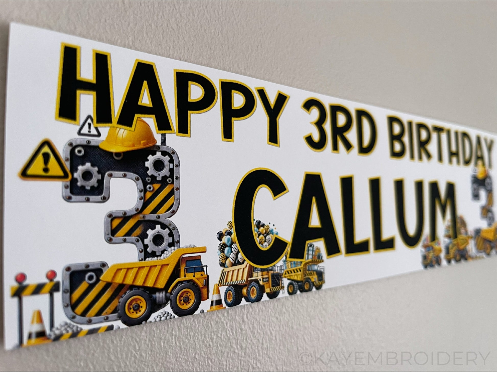 Personalised Birthday Banner featuring a yellow and black construction theme with trucks, gears and balloons