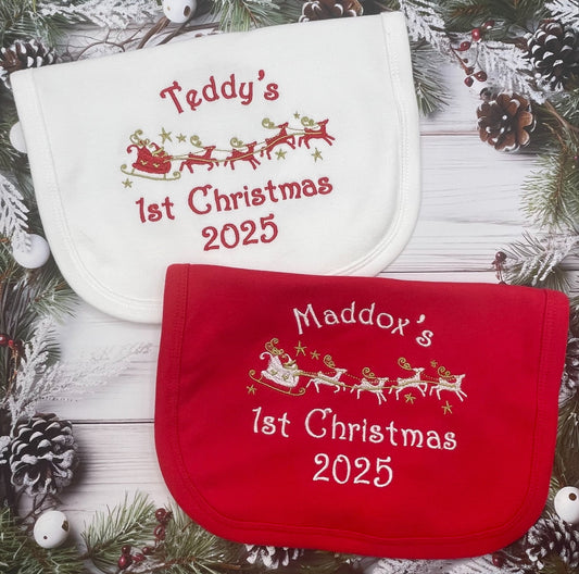 Red or white baby bib with name and 1st Christmas 2025' text on a festive background