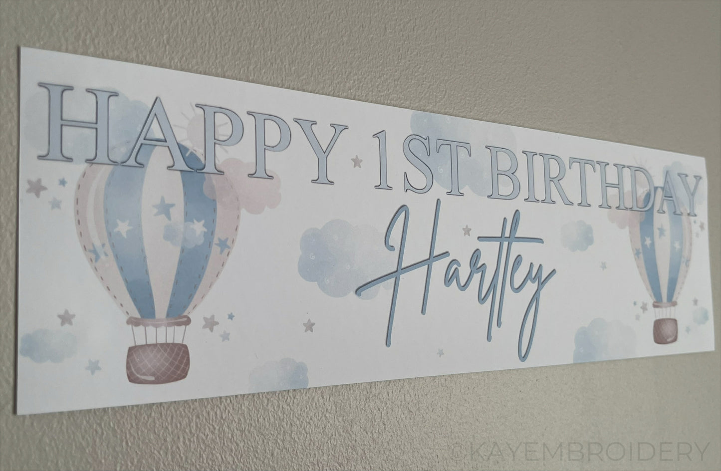 In the Sky 1st Birthday banner in blue with hot air balloons, clouds and stars, personalised with happy 1st birthday and name