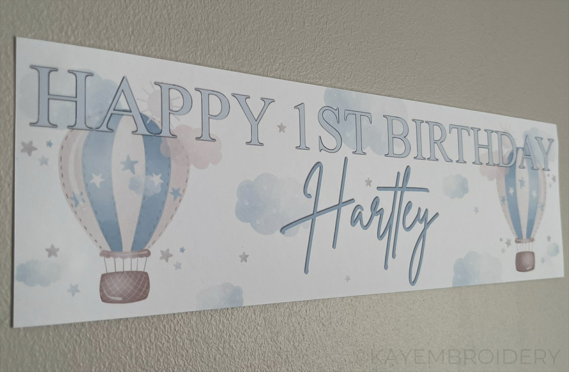 In the Sky 1st Birthday banner in blue with hot air balloons, clouds and stars, personalised with happy 1st birthday and name