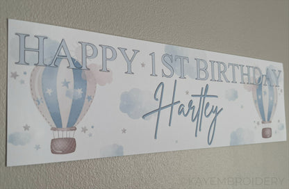 In the Sky 1st Birthday banner in blue with hot air balloons, clouds and stars, personalised with happy 1st birthday and name