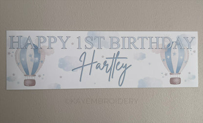 In the Sky 1st Birthday banner in blue with hot air balloons, clouds and stars, personalised with happy 1st birthday and name
