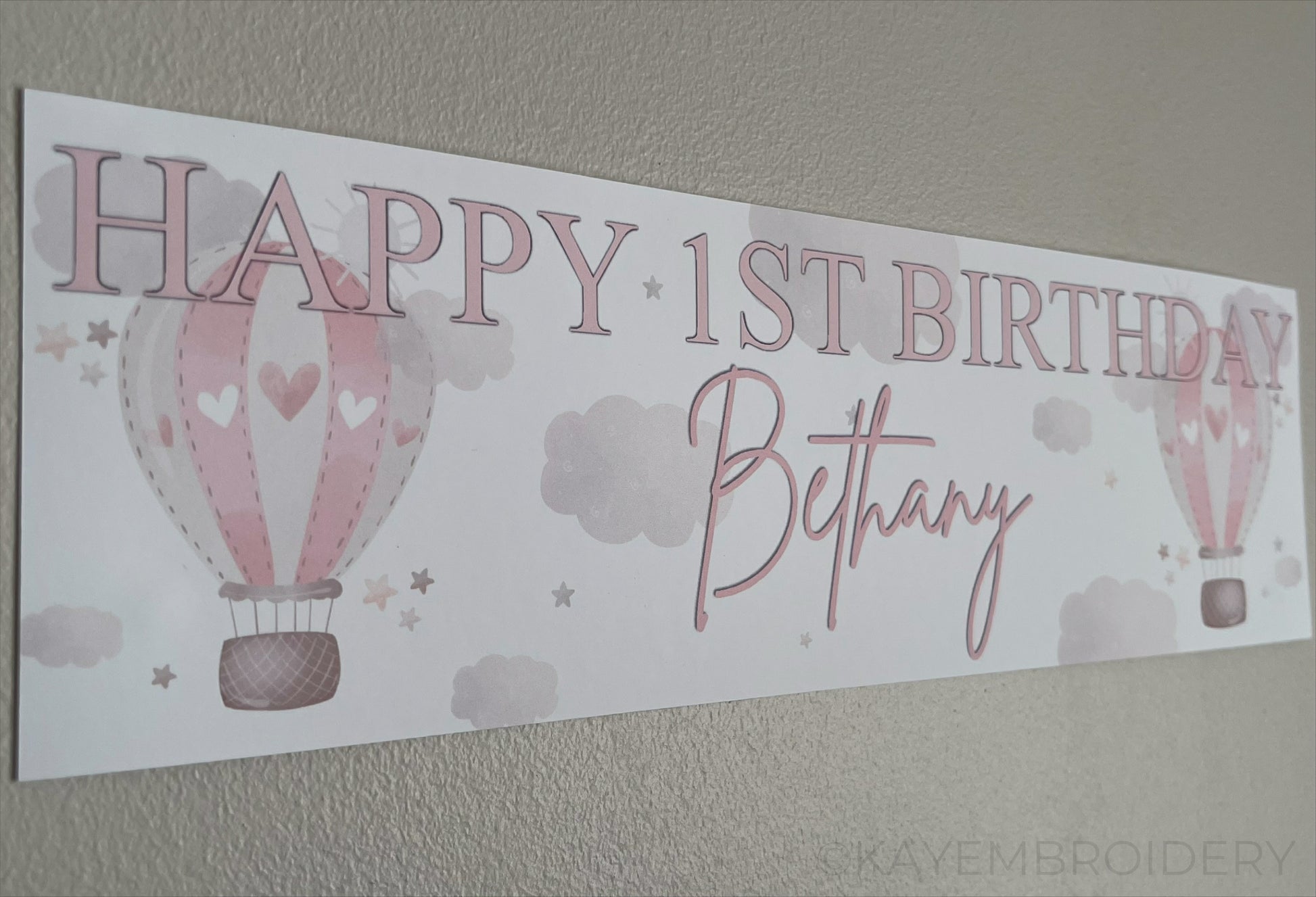 In the Sky 1st Birthday banner in pink with hot air balloons, clouds and stars, personalised with happy 1st birthday and name
