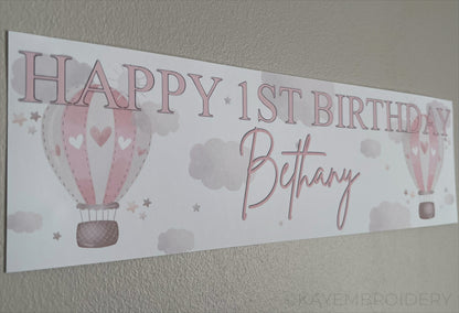 In the Sky 1st Birthday banner in pink with hot air balloons, clouds and stars, personalised with happy 1st birthday and name